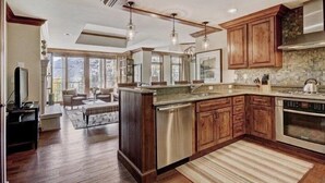 A spacious kitchen with wooden cabinets, a stainless steel dishwasher, and a large island. - Vail Ritz-carlton 3 Bedroom Residence in Lionshead Village (Vail)
