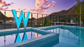 A swimming pool with a large 'W' logo, surrounded by a fence and a mountainous landscape in the background. - Downtown Aspen Luxury 2 Bedroom Residence (Aspen)