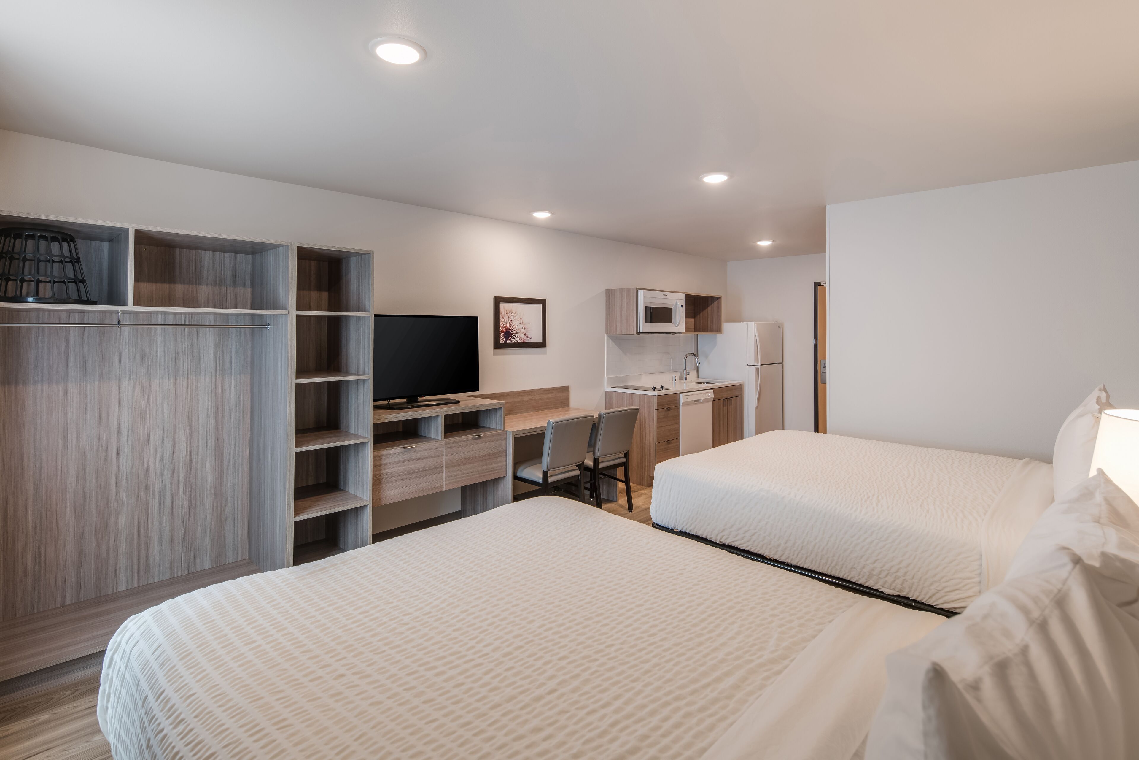 Une chambre d’hôtel avec deux lits, un bureau, une télévision et une armoire.