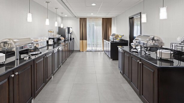Cozinha de hotel moderna, com balcão extenso, serviço de buffet e vista para a área de refeições.