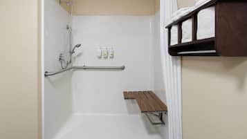 Un espace douche équipé d’un banc, de barres d’appui et de produits de toilette.
