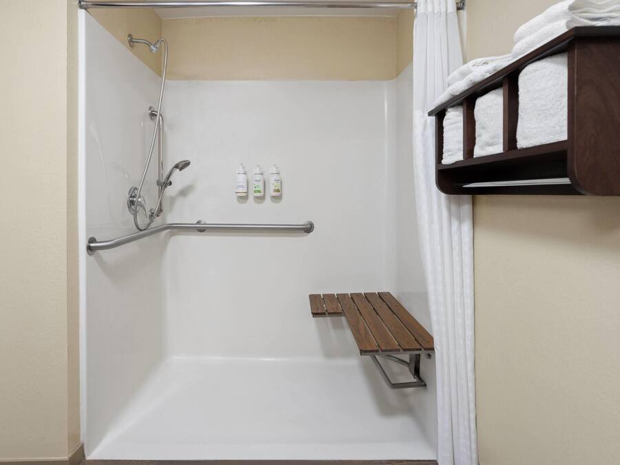 Un espace douche équipé d’un banc, de barres d’appui et de produits de toilette.