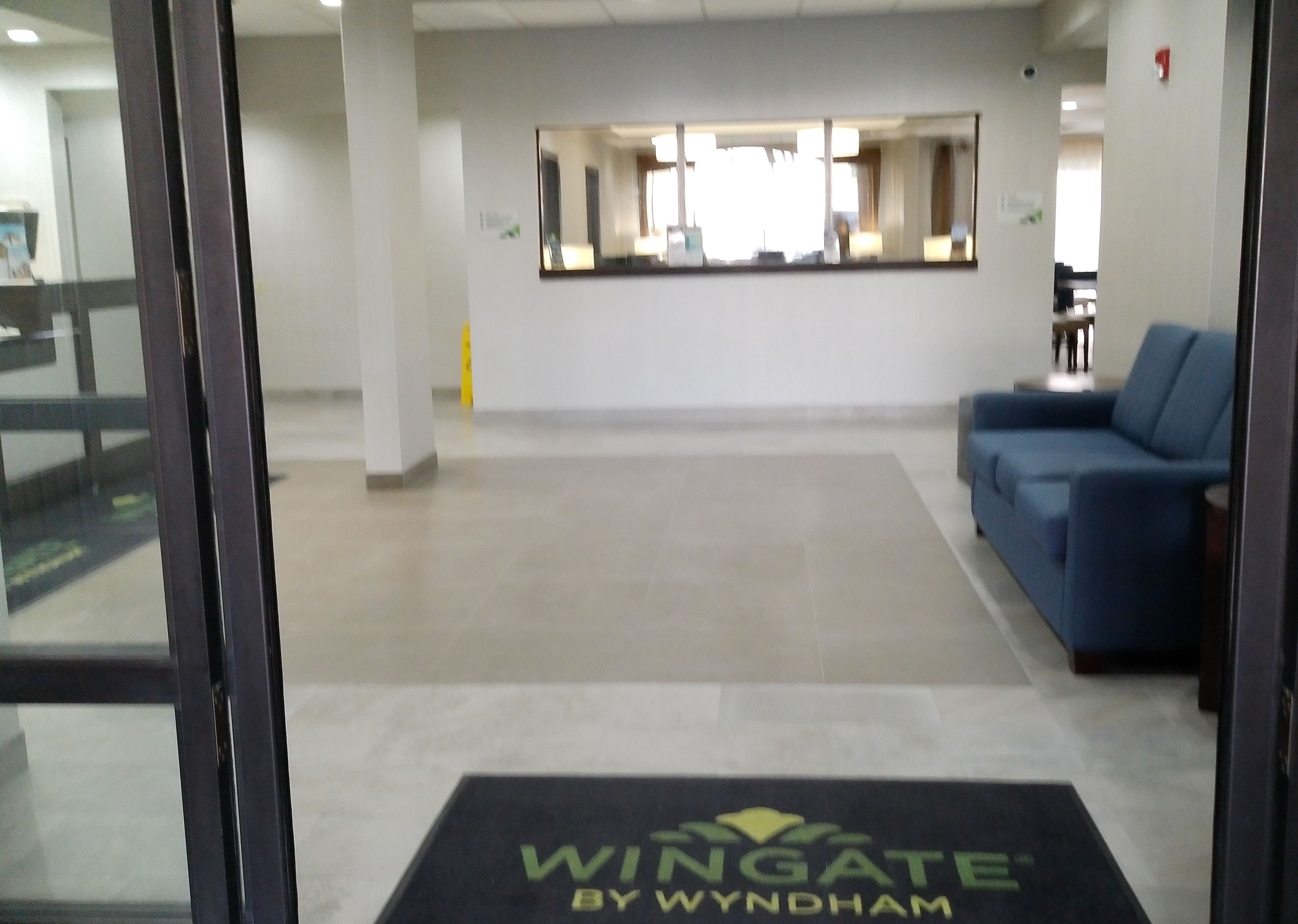 Un área de recepción con un sofá azul, una mesa de recepción y un logotipo en el suelo.