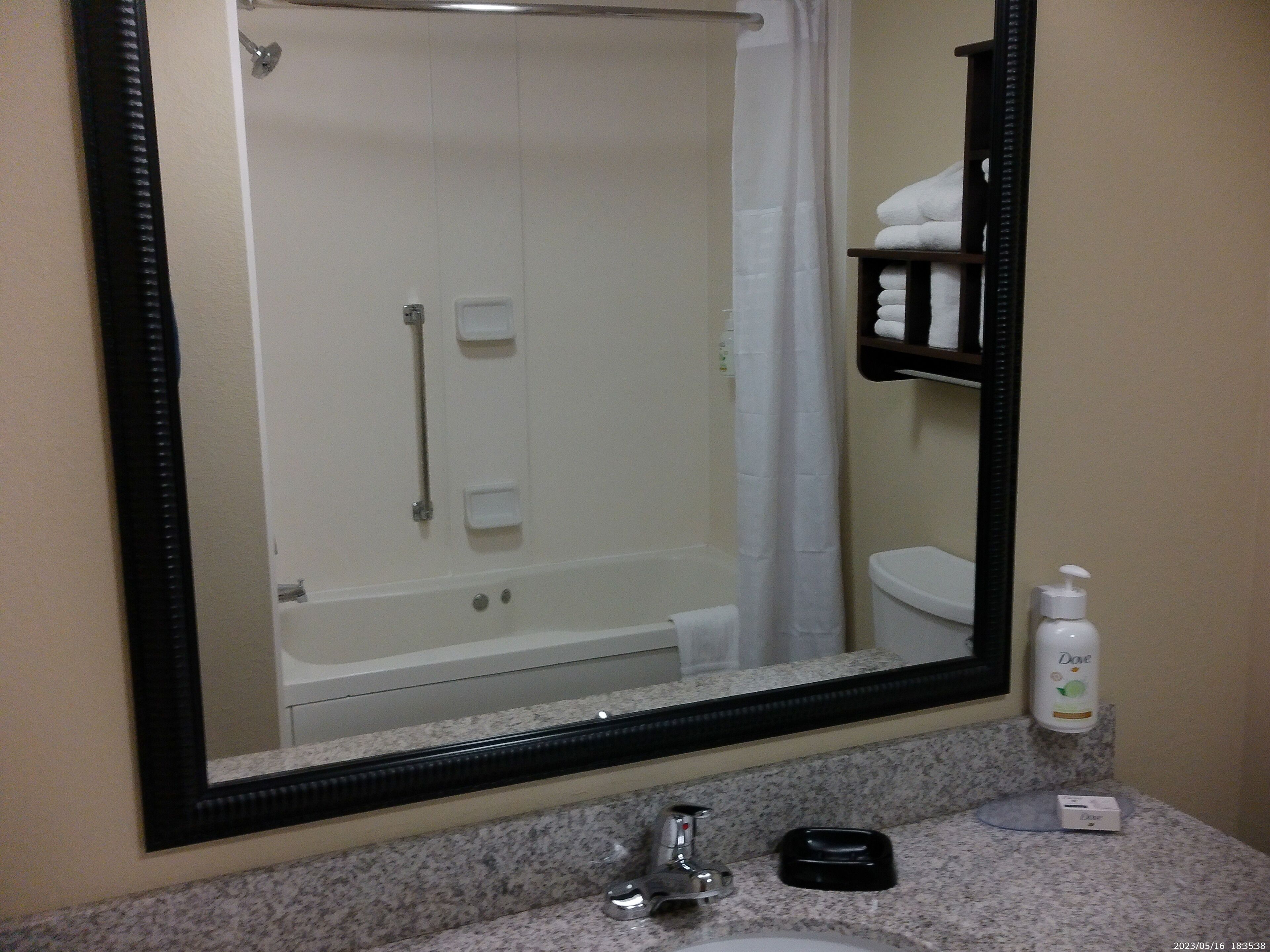 A bathroom with a large mirror, a sink, a towel rack, and a shower.