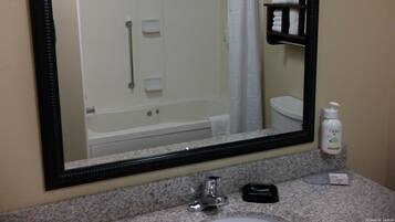Un baño con un espejo grande, un lavabo, un perchero para toallas y una ducha.