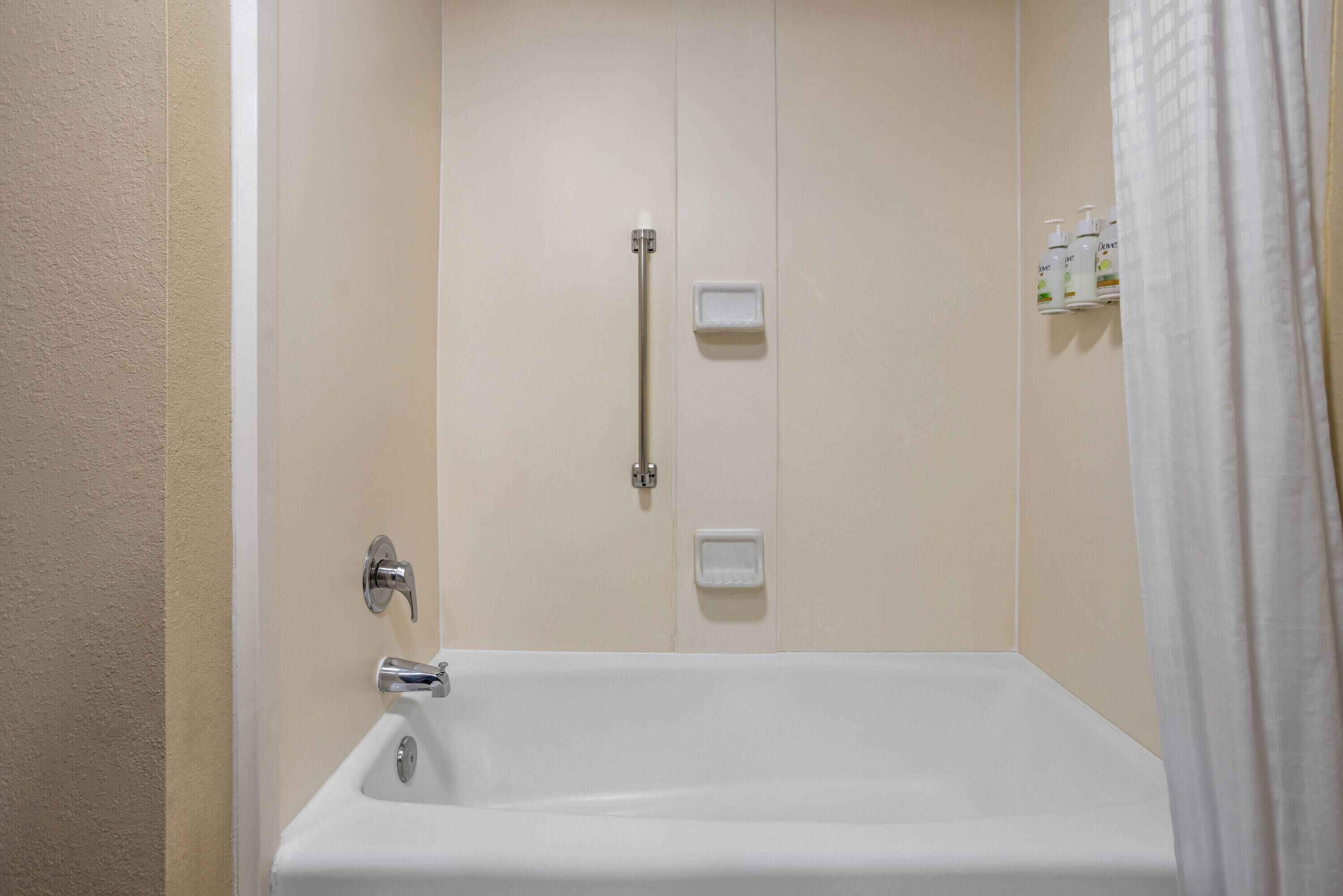 A bathroom with a white sink, a shower curtain, and a hand dryer on the wall.