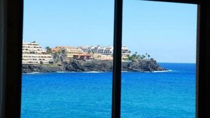 Une vue sur la côte, avec un bâtiment situé sur un promontoire rocheux, dominant la mer.