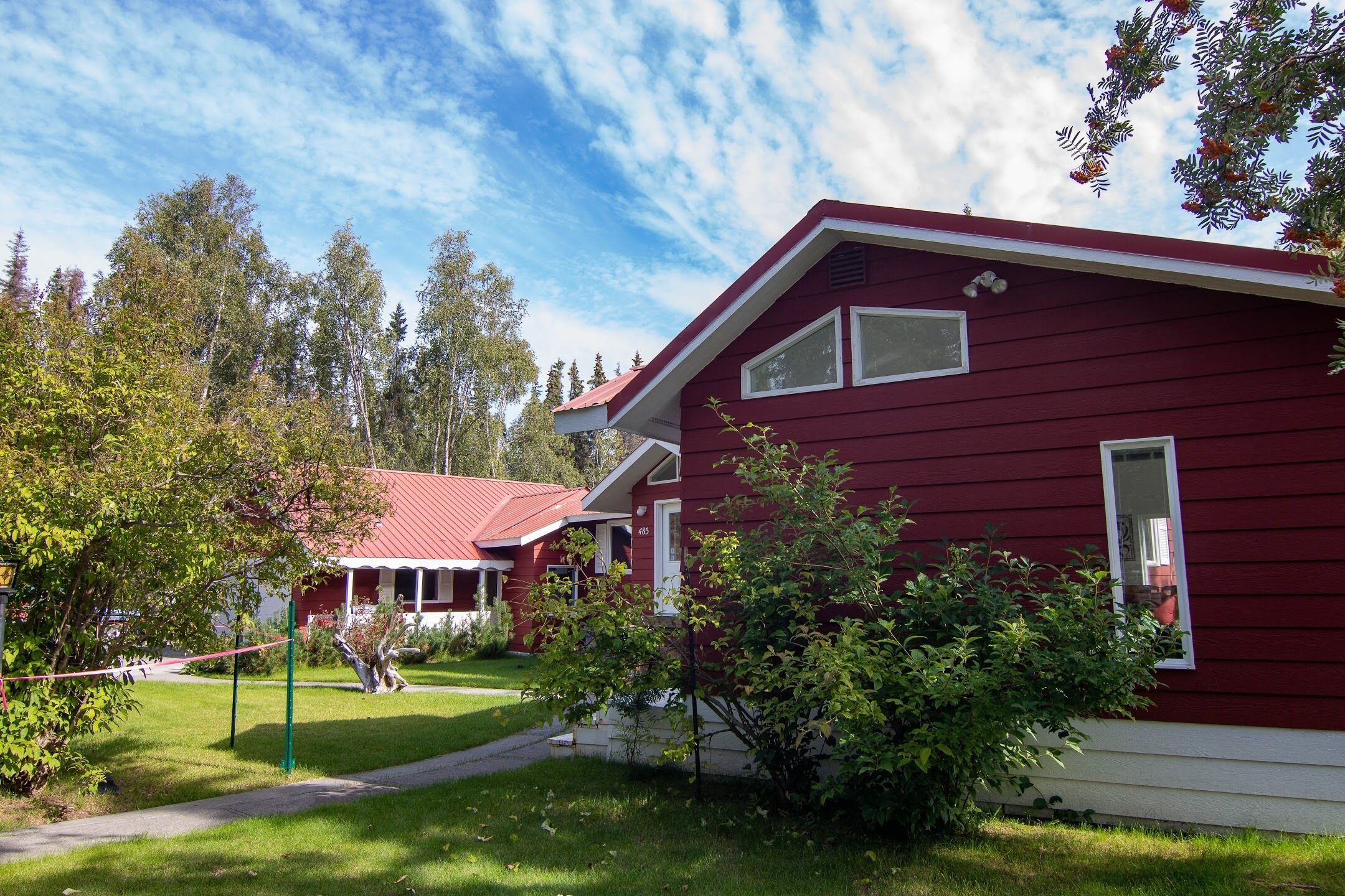 A red house with a white porch and a small garden.