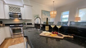A modern kitchen with white cabinetry, stainless steel appliances, a marble countertop, and a central island with food items and a wine bottle. - 600ft from Beach Ocean view Heated Pool 4BR 4ba sleep11. 44 Summer Place 30A (Santa Rosa Beach)