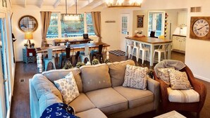 A spacious living area with a large sofa, a dining table with chairs, and a kitchen area with a bar.