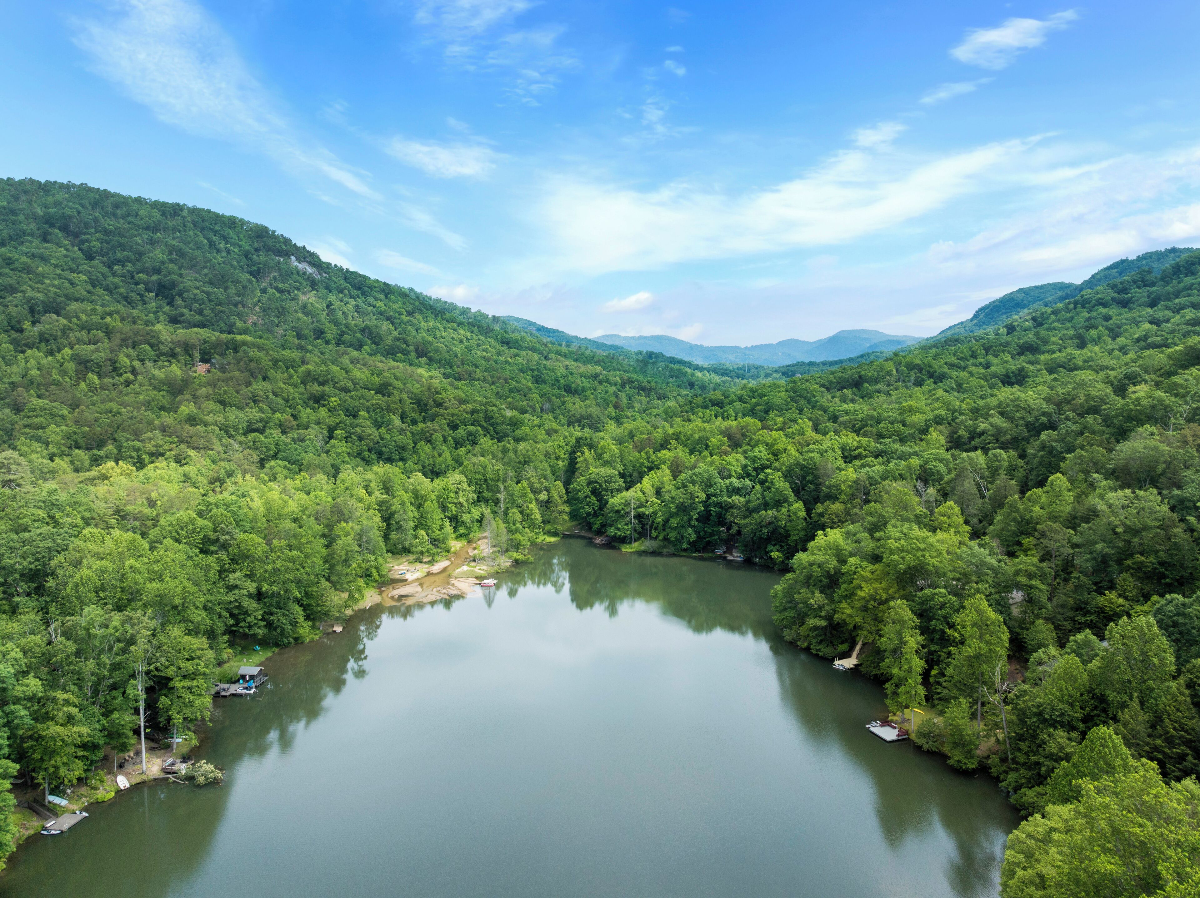 A serene lake surrounded by dense forest and hills.