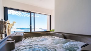 Un bain à remous avec vue sur la mer et les montagnes, grâce à de grandes fenêtres.