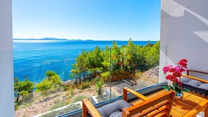 Un balcon avec vue sur la mer, des meubles en bois et un vase de fleurs.