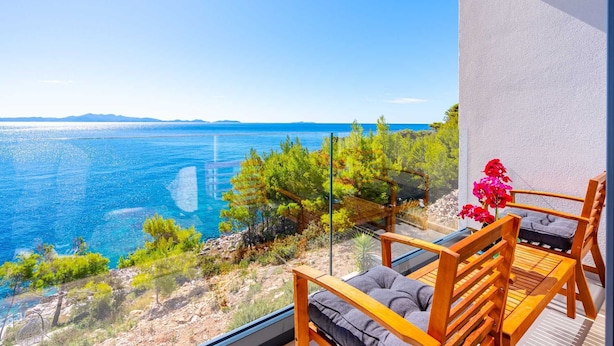 Un balcon avec vue sur la mer, des meubles en bois et une plante en pot.