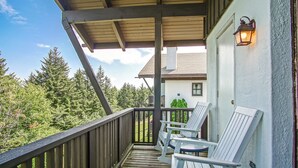 A wooden deck with two white Adirondack chairs and a lantern on a building's exterior wall. - Whistlepunk 13 Spacious 4 Br Condo Slope Side (Snowshoe)