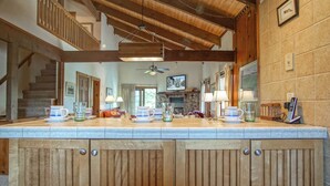 A kitchen with wooden cabinets, a stone fireplace, and a large island with various kitchen items. - Whistlepunk 13 Spacious 4 Br Condo Slope Side (Snowshoe)
