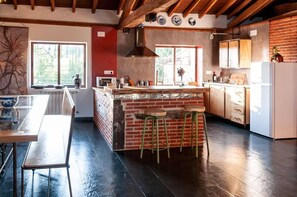 A kitchen with a brick island, wooden stools, and a large window.