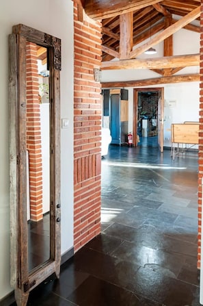 A spacious room with a brick wall, a wooden door, and a polished floor.