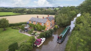 A riverside house with a boat dock, a garden, and a field in the background. - Two bedroomed property situation in a beautiful secluded location with patio area overlooking fields (Wootton Wawen)