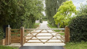 A gated pathway leading into a park with a paved walkway and lush greenery. - Two bedroomed property situation in a beautiful secluded location with patio area overlooking fields (Wootton Wawen)