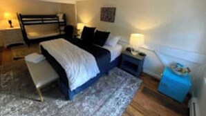 Une chambre à coucher avec un lit, des tables de chevet, une lampe et une petite armoire bleue.