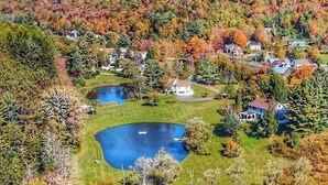 A residential area with houses, a pond, and autumn-colored trees. - Deluxe King - 2nd floor in Historic Inn (West Dover)