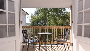 A wooden deck with a table and four chairs, a wooden railing, and a view of trees and a house in the background. - Deluxe King - 2nd floor in Historic Inn (West Dover)