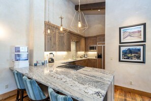 A kitchen with a large island, wooden cabinets, and pendant lighting.