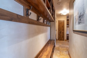 Un couloir avec un banc en bois, des patères fixées au mur et une porte au fond.