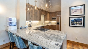 A kitchen with a large island, wooden cabinets, and modern lighting fixtures.