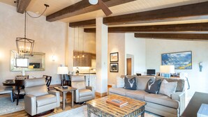A spacious living room with a wooden coffee table, a beige sofa, and a dining area with a table and chairs.