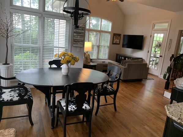 A dining area with a round table, black chairs with cowhide upholstery, and a vase with yellow flowers. - LUXURY HOME INCLUDES GOLF CART walking distance to historic village center (Pinehurst)