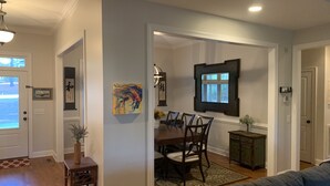 A dining area with a wooden table and chairs, a painting on the wall, and a view through an open door. - LUXURY HOME INCLUDES GOLF CART walking distance to historic village center (Pinehurst)