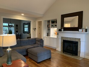 A living room with a sectional sofa, ottoman, and a fireplace. - LUXURY HOME INCLUDES GOLF CART walking distance to historic village center (Pinehurst)