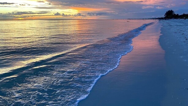 Ein Strand mit ruhiger See und Sonnenuntergang.