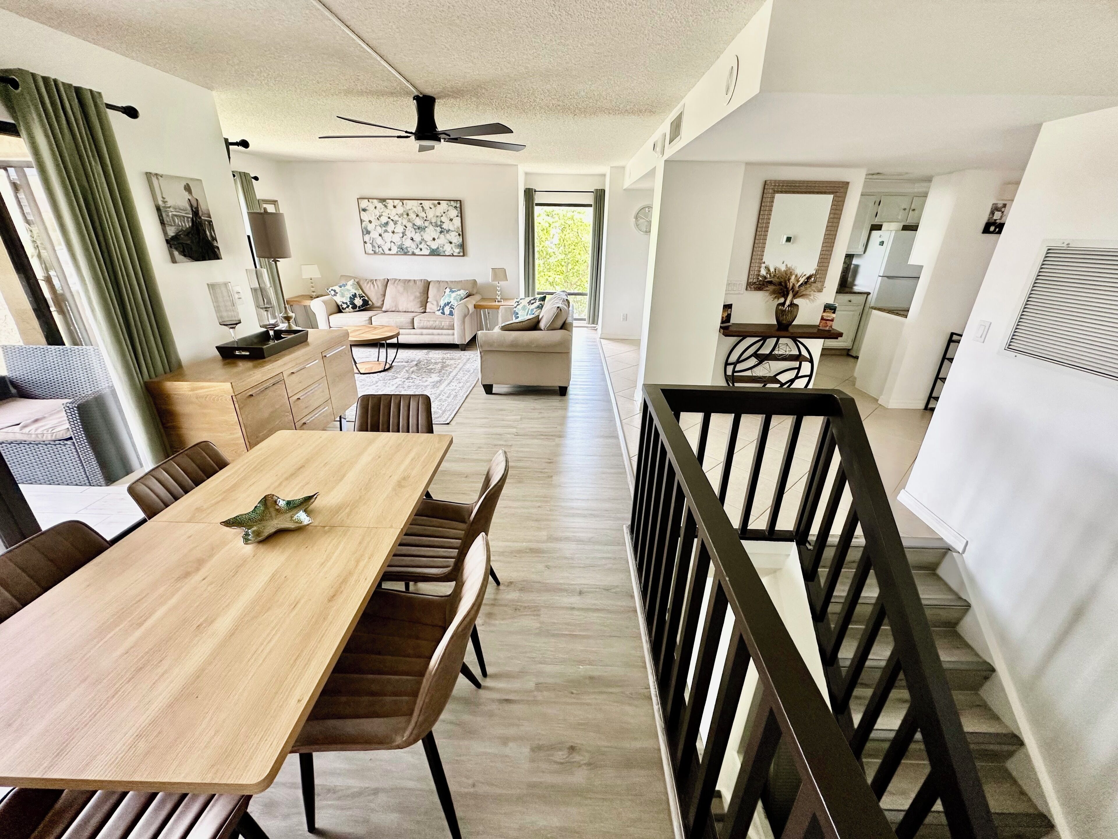 A spacious living area with a dining table, sofas, and a kitchen in the background.