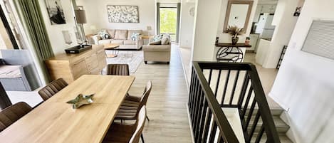 A spacious living area with a dining table, sofas, and a kitchen in the background.