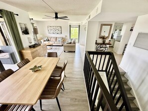 Amplia sala de estar con una mesa de comedor, sofás y una cocina al fondo.