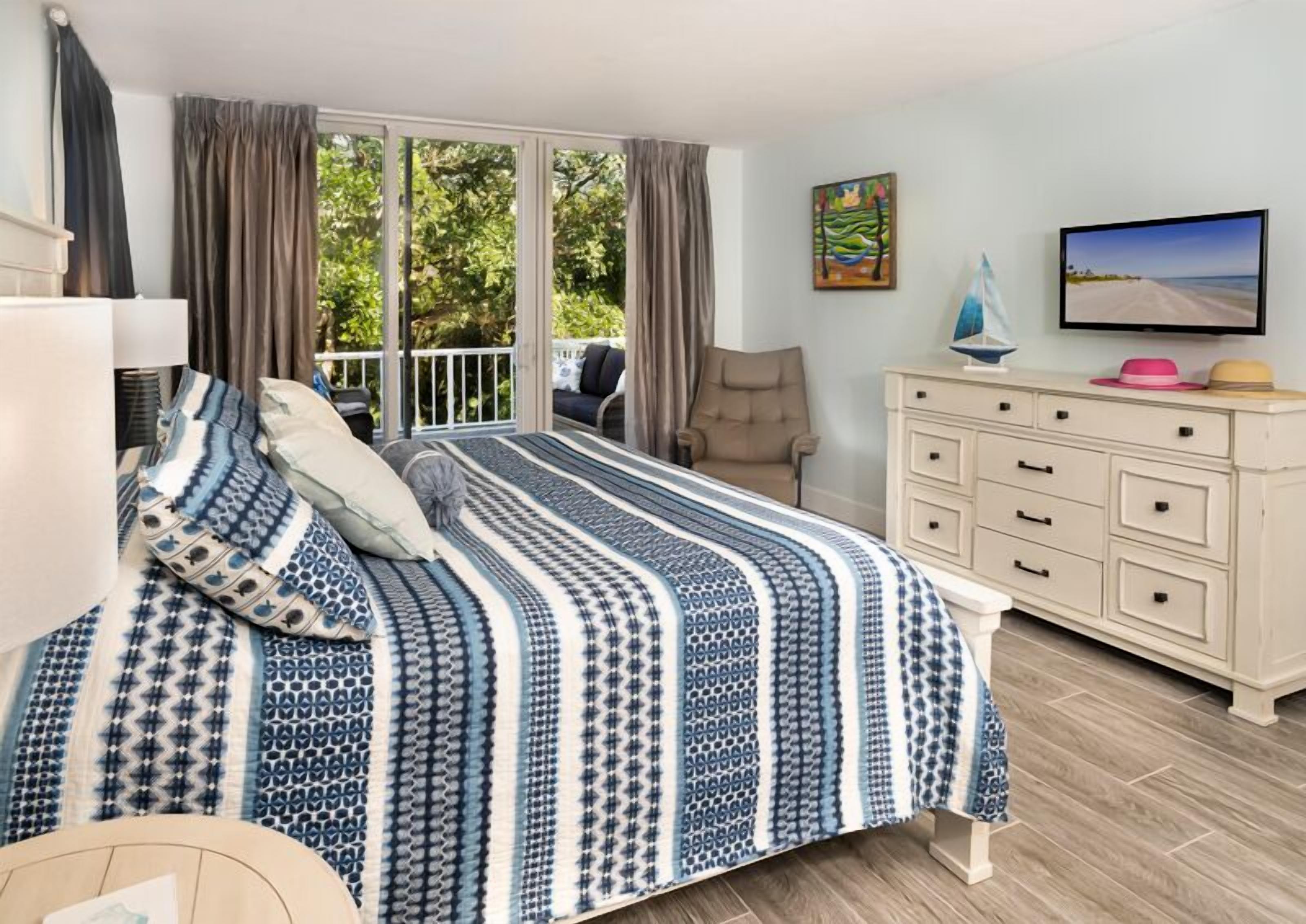 Une chambre à coucher avec un grand lit, une commode, une chaise et un téléviseur.