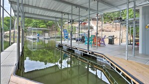 Un espacio al aire libre techado con un muelle que se adentra en el agua, con asientos y una parrilla.
