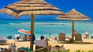 A beach with thatched umbrellas and lounge chairs. - Hidden Gem! Turtle Bay Hideaway (Kahuku)