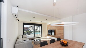 A modern living room with a sofa, dining table, and a view of the outside.