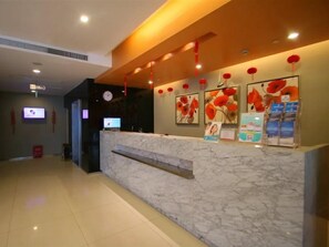 A hotel reception area with a marble counter, red lanterns, and framed artwork on the wall. - Jinjiang Inn (Shanghai Changzhong Road Subway Station) (Shanghai)