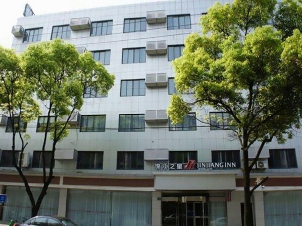 A multi-story building with a commercial ground floor, air conditioning units on the facade, and a sign with Chinese characters. - Jinjiang Inn (Shanghai Changzhong Road Subway Station) (Shanghai)