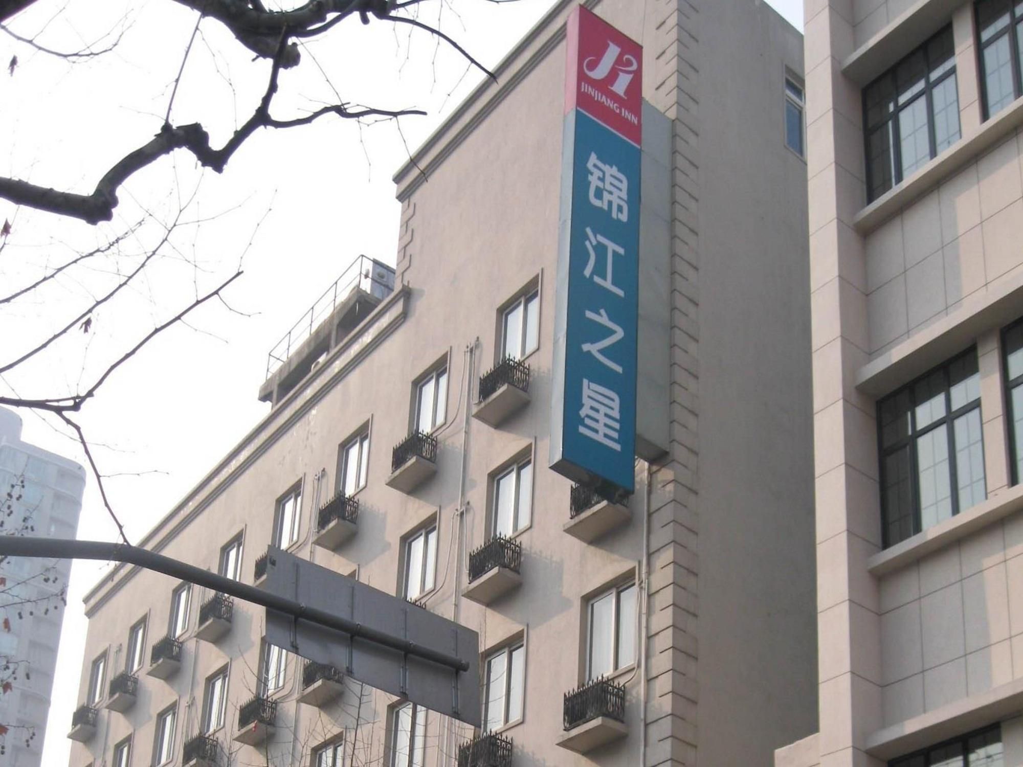 A building with multiple windows and balconies, a sign for Jinjiang Inn, and a clear sky.