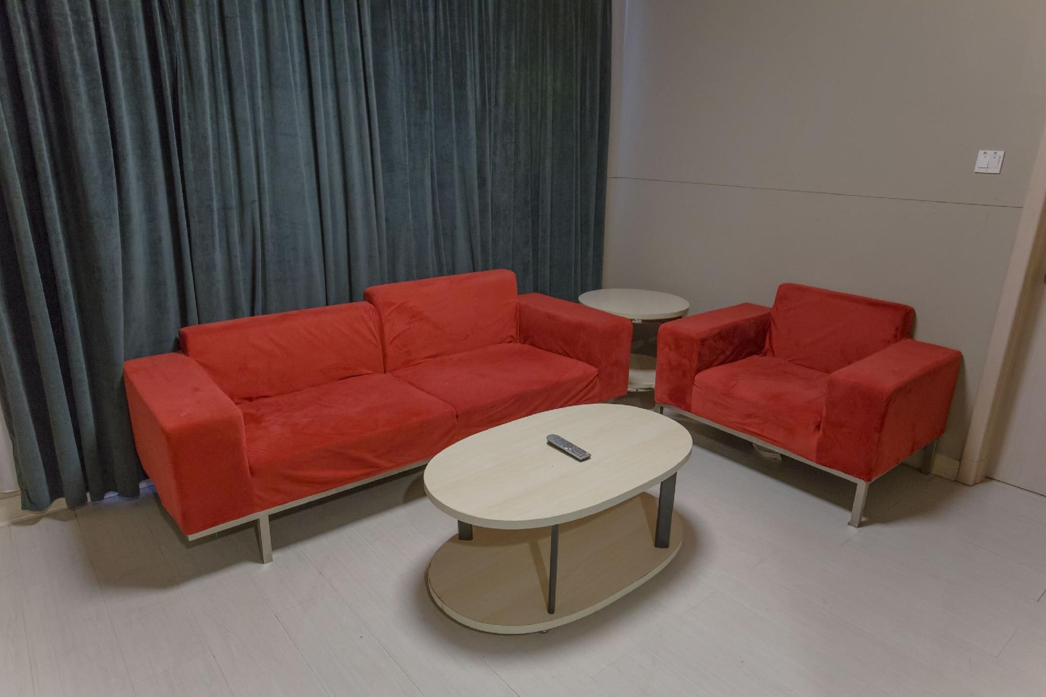 A room with a red sofa set, a small round table, and a red armchair.