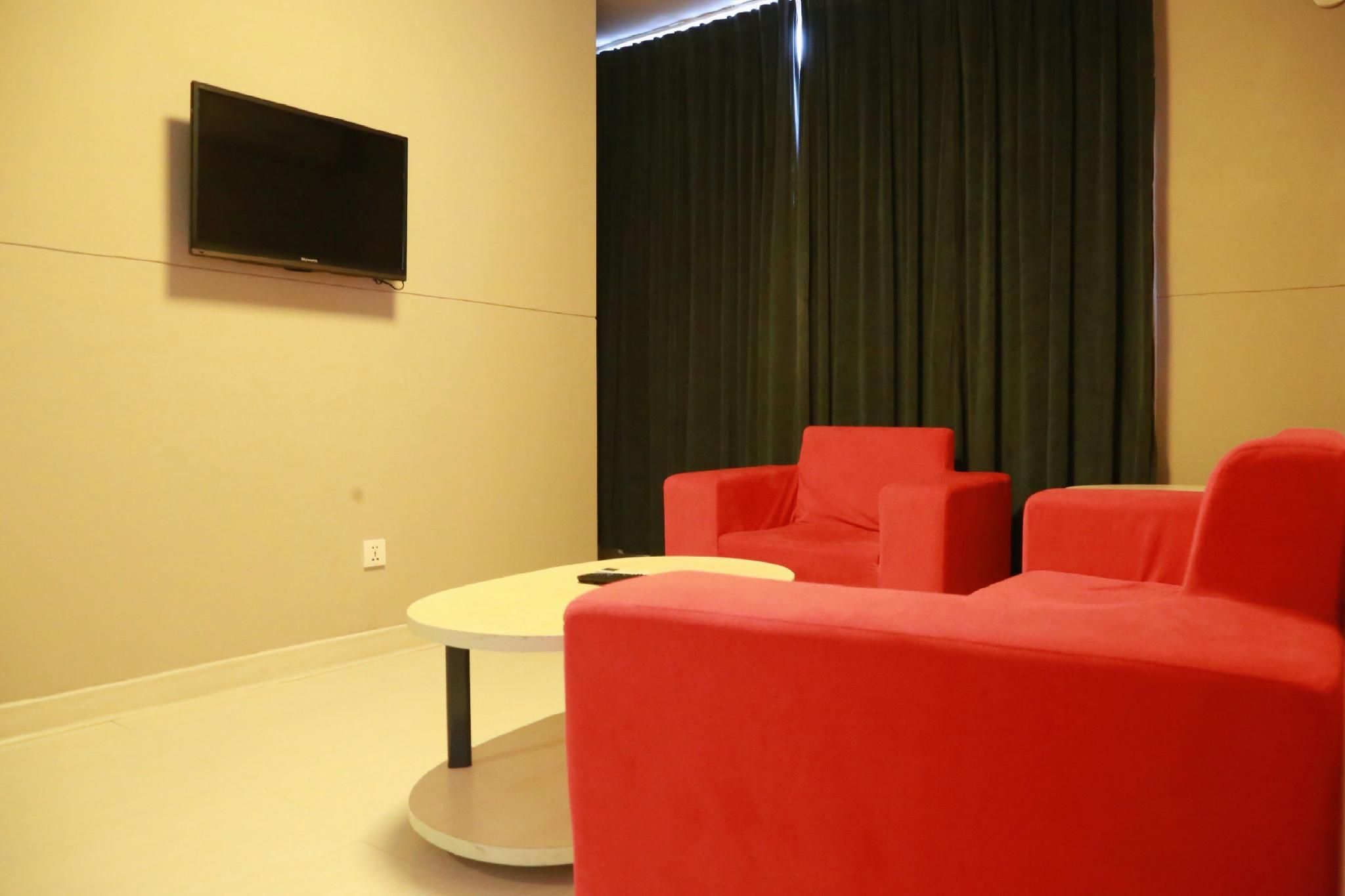 Une pièce avec un téléviseur à écran plat fixé au mur, une table ronde et deux chaises rouges.