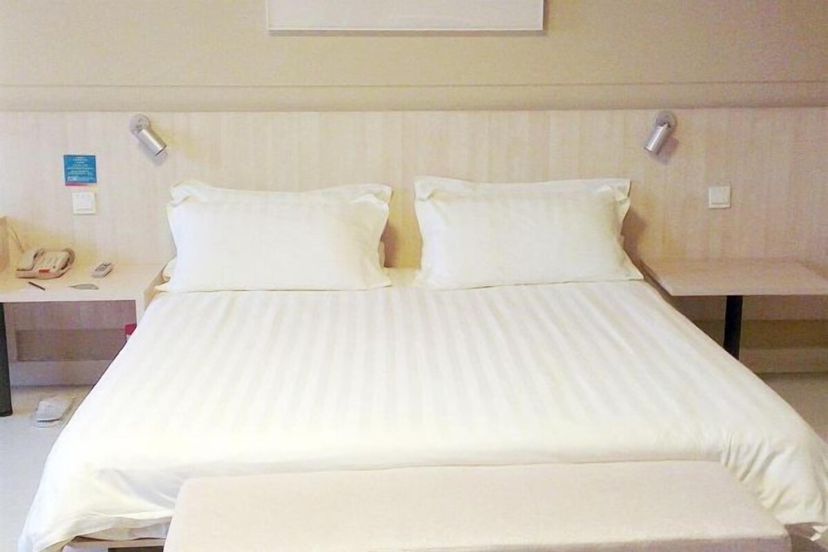 A hotel room with a bed, bedside tables, and a telephone.
