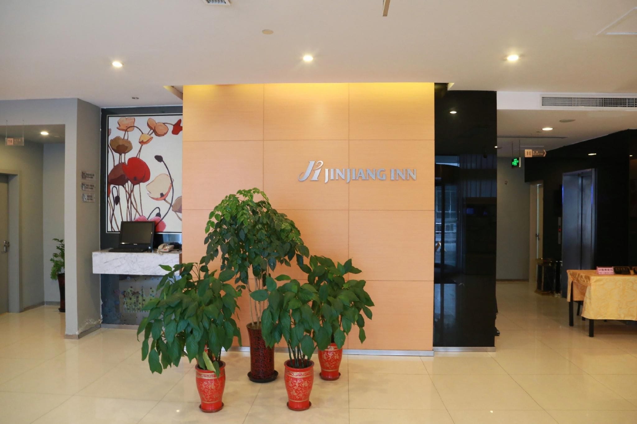 A reception area with a sign for Jinjiang Inn, a reception desk, and potted plants.
