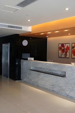A modern reception area with a marble counter, a clock, and artwork on the wall. - Jinjiang Inn (Shanghai Changzhong Road Subway Station) (Shanghai)